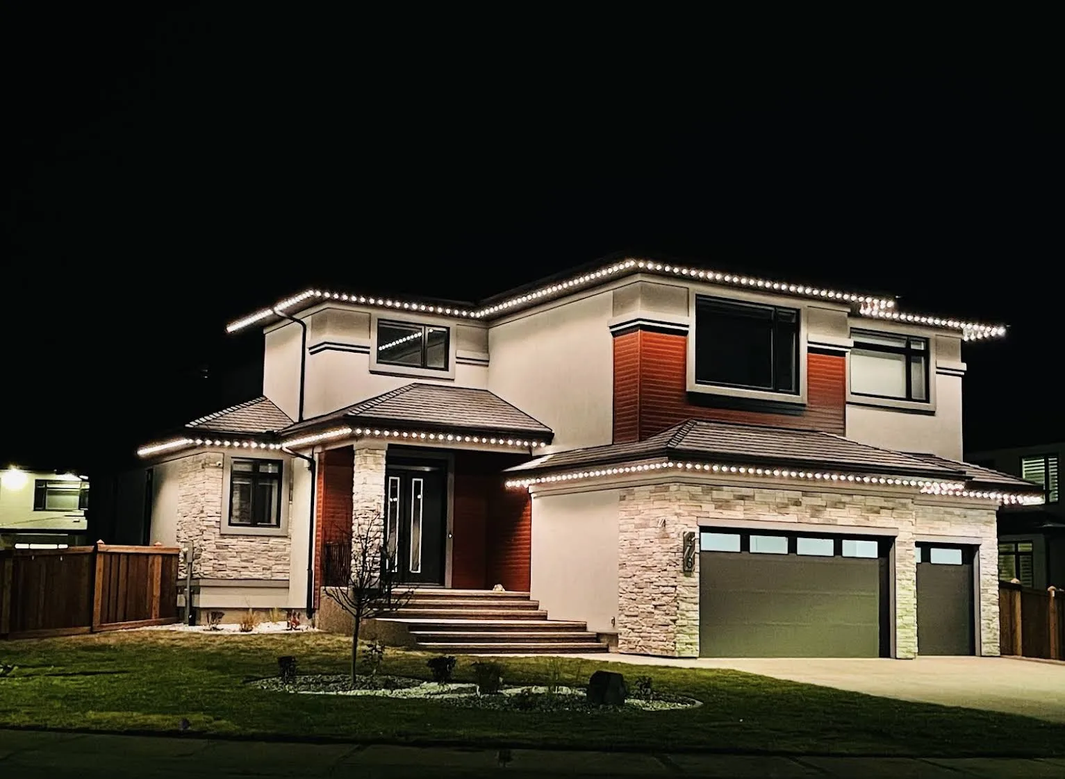 Modern home illuminated with warm-white permanent roofline lighting